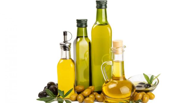 Álava modifica los tipos reducidos de IVA para productos esenciales como aceites y pastas. Imagen de unas botellas de aceite de oliva y unas olivas a su alrededor