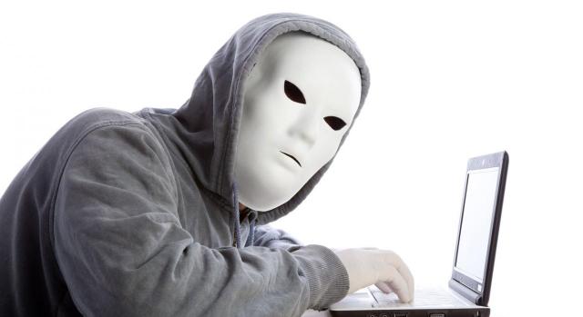 Hombre hacker con máscara y guantes usando un portátil. Falciani