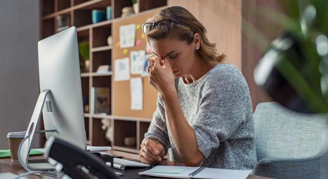 La Agencia Tributaria incrementa las facilidades de pago de las deudas tributarias. Imagen de una mujer de negocios con dolor de cabeza en la oficina