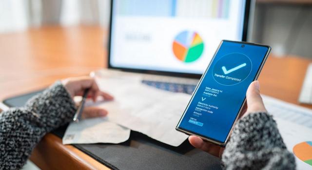 Nueva funcionalidad de la APP de la Agencia Tributaria para pagar, aplazar y consultar deudas. Imagen de unas manos de mujer con un movil utilizando la app del banco