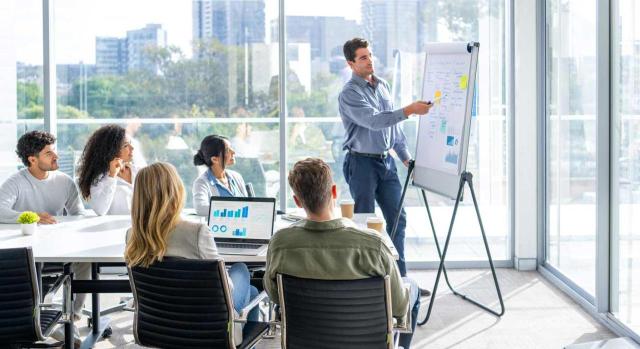 IVA: devengo de servicios de asesoría empresarial. Gente de negocios viendo una presentación en la pizarra