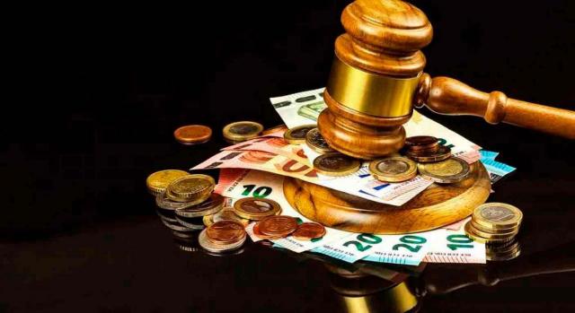 Ley fraude fiscal. Imagen de mazo de juez golpeando encima de un montón de billetes y monedas de euros