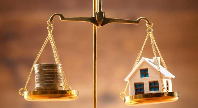 Deducción por inversión en vivienda habitual IRPF: aun habiendo varios copropietarios, aunque uno asuma el pago total de la hipoteca, solo se puede deducir las cantidades que correspondan en función de su porcentaje de titularidad sobre la vivienda. Imagen de balanza dorada en la que hay en un platillo monedas y en otra una casita