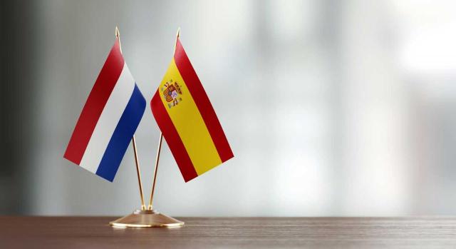 El TS rechaza la aplicación de la exención de los cánones o royalties satisfechos por la entidad residente en España a su matriz residente en los Países Bajos y resuelve el tipo de retención es el previsto en la normativa interna y no en el CDI. Imagen de la bandera de Holanda y España sobre un escritorio