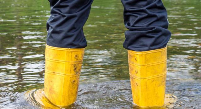 Persona con botas de agua en una inundación causada por temporal. Beneficios fiscales