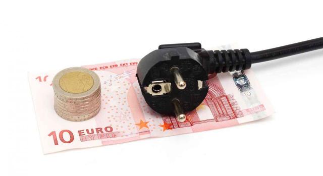 Álava prorroga hasta el 30 de junio de 2022 la suspensión IVPEE y las rebajas del IVA y del Impuesto sobre la Electricidad. Imagen de un enchufe negro y unas monedas apiladas sobre un billete de 10 euros