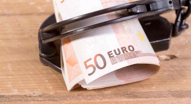 Proyecto Devolución retenciones. Billetes de 50 euros enrollados dentro de las esposas sobre una mesa