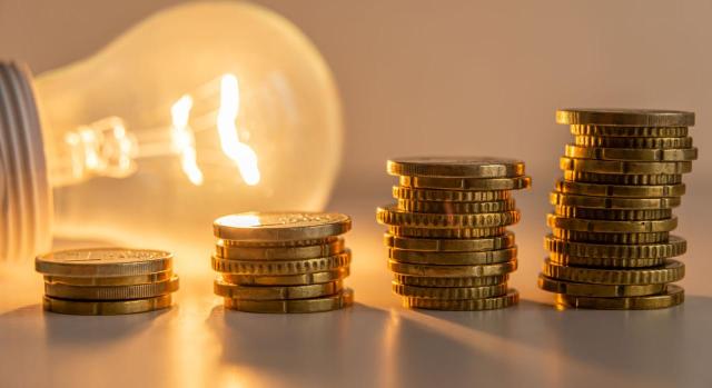 Revocación de liquidaciones firmes del IAE y la devolución de lo ingresado por resultar contrarias a la doctrina del STS de 12 de mayo de 2021, sobre el encuadramiento de la actividad de comercialización eléctrica. Imagen de una bombilla y unas monedas