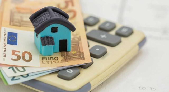 Aprobación Norma Foral del Impuesto sobre Bienes Inmuebles en Gipuzkoa. Imagen de una calculadora y encima unos billetes y una casita