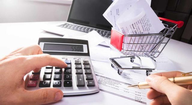 No cabe aplicar la deducción del 1% del importe neto de la cifra de negocios en concepto de gastos incurridos en atención a clientes si no va acompañado de su vinculación directa en el desarrollo de la actividad. Imagen de las manos de una persona calculando una factura con una calculadora