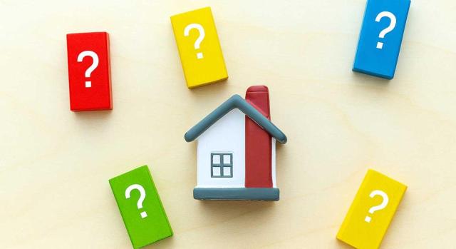 IIVTNU no liquidado por el ayuntamiento que impide su deducibilidad en IRPF. Imagen de una casita con cajas a su alrededor de colores con un interrogante