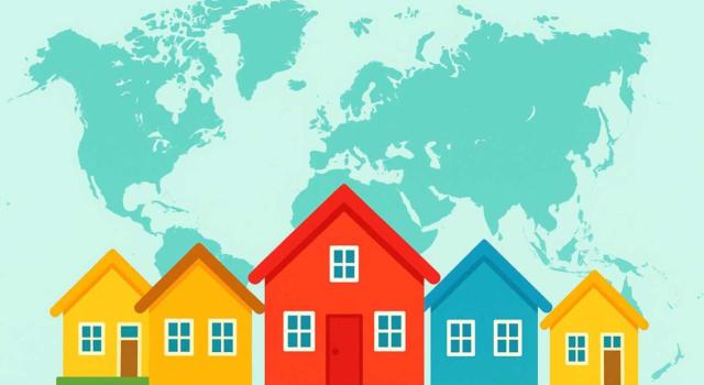 IP: deuda relacionada con inmueble que se ha aportado a una sociedad Análisis fiscal en IP sobre la deducibilidad o no de la deuda personal derivada de un préstamo para la adquisición, construcción y mejora de un inmueble aportado a una sociedad española por un contribuyente no residente. Imagen de casas de colores sobre un mapamundi de fondo