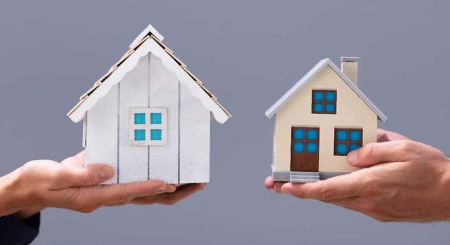 Modificación de contratos de arrendamiento de vivienda en zonas tensionadas con el objetivo de aplicación de reducciones en IRPF. Imagen de dos manos en el que cada una sostiene una casa