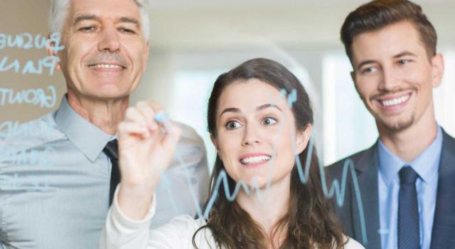 Donación de participaciones de empresa familiar: requisitos para la exención en IP y la reducción en ISD según la DGT. Imagen de tres personas mirando una pizarra digital en la que la chica está escribiendo