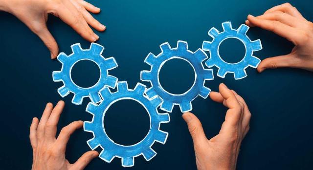 Compensación de BINS en una fusión por absorción inversa Compensación de BINS en una operación de fusión por absorción inversa analizada por la DGT. Imagen de cuatro manos colocando engranajes para que conecten