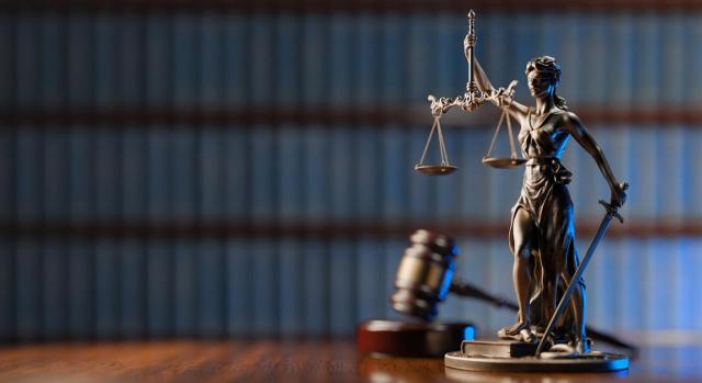 Es nula de pleno derecho la sanción si el órgano sancionador no motiva el rechazo o denegación de la prueba de descargo. Diosa de la Justicia y el martillo del juez como símbolo de la ley y el orden sobre fondo de libros