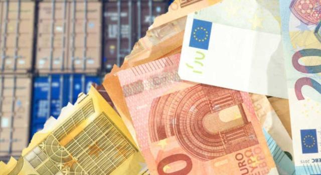 La DGT determina cuándo el importe de un canon se debe adicionar al precio de las mercancías a efectos de determinar el valor en aduana. Imagen de contenedores  y billetes por delante de ellos