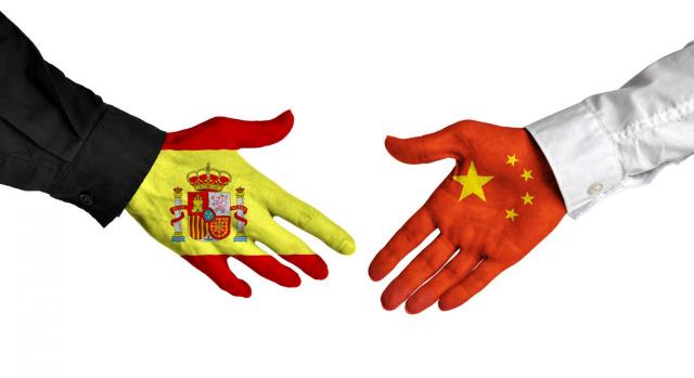 Convenio entre España y China. Dos personas estrechandose las manos pintadas con las banderas de España y China
