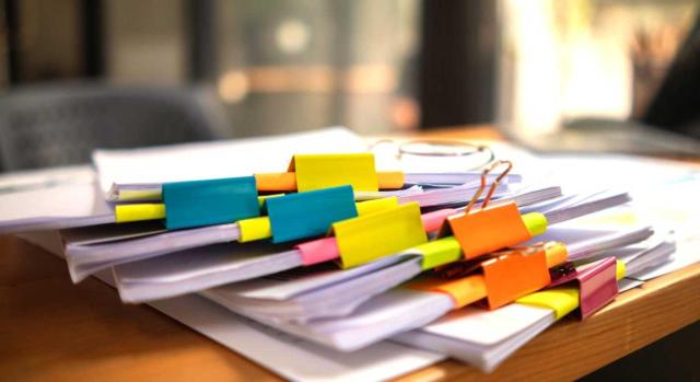 La información obtenida en el curso de un procedimiento inspector se puede utilizar para la regularización de los ejercicios a los que posteriormente se amplíe el alcance o extensión del procedimiento. Imagen de varios documentos apilados y seleccionados por colores encima de una mesa de trabajo