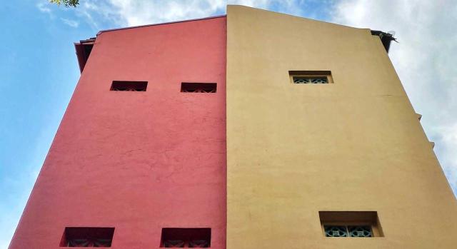 No es admisible que, a efectos del ITP, medio bien tenga un valor real y el otro medio bien otro distinto, ya que ello vulnera frontalmente los principios de capacidad económica y de justicia tributaria. Imagen de un edificio alto que la mitad de su fachada es roja y la otra mitad amarillo