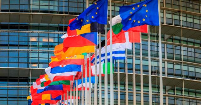Actualizada la lista de la UE de países y territorios no cooperadores a efectos fiscales El Consejo de la Unión Europea actualiza la lista de países y territorios no cooperadores a efectos fiscales. Imagen de la puerta de un edificio con todas las banderas de la UE