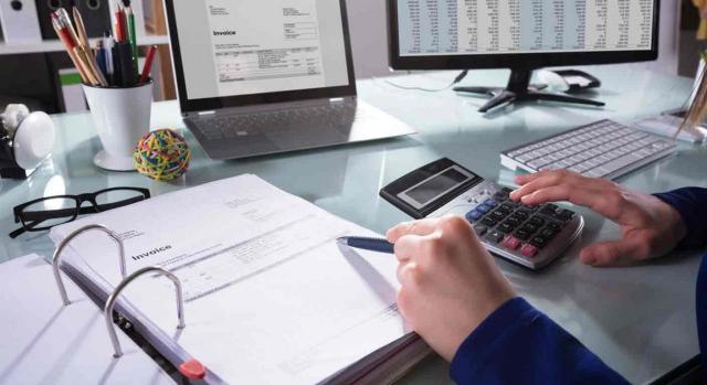 Campaña renta DGT TEAC: Un empresario calcula una factura con la calculadora y el ordenador