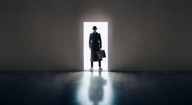 Inspección en sede empresa. Imagen de hombre con maletín entrado en un local oscuro