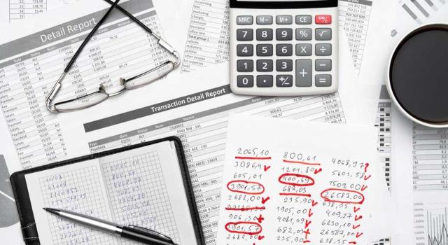 Recurso contra el TEAC: Estimación por error contable neutralizado en el Impuesto de Sociedades y validez de la prueba pericial aportada. Imagen de un escritorio lleno de cuentas, calculadora, cuaderno, notas y gafas