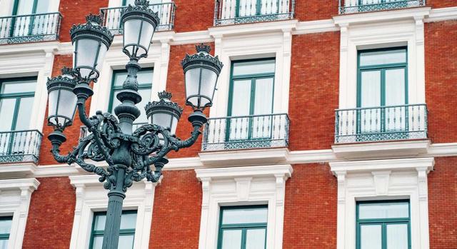 Un comunero no residente puede solicitar mediante el modelo 210 devolución del exceso en caso de que el ingreso a cuenta realizado por la comunidad de bienes constituida en España resulte superior. Imagen de la fachada de un edificio y una farola delante de él