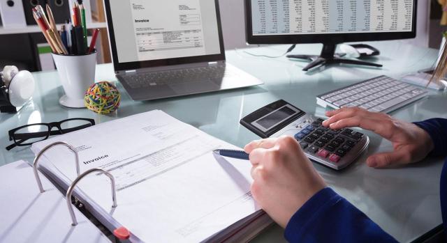 Factura electrónica en el sector privado. Imagen de las manos de un hombre con una calculadora, calculando los importes de una factura