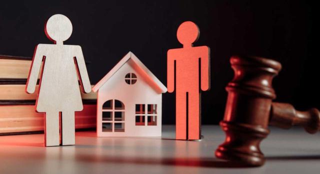 El Tribunal Supremo reitera su doctrina respecto a la exención por reinversión en vivienda habitual respecto a los supuestos de separación, divorcio o nulidad matrimonial. Imagen de unas figuras de personas de madera y una casa junto a un mazo de juez