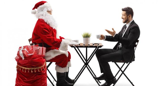 Fiscalidad de regalos, cestas y cenas con motivo de la Navidad. Imagen de Santa Claus y un hombre de negocios teniendo una conversación en una mesa de café