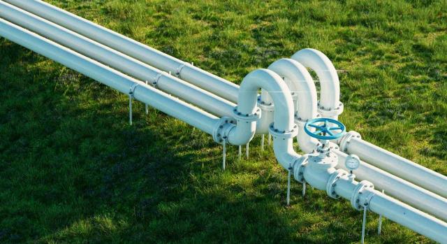 La tasa por el uso privativo de dominio público por las instalaciones de gas, agua e hidrocarburos debe atender a su intensidad. Imagen de un gasoducto blanco y oleoducto sobre un exuberante fondo herboso