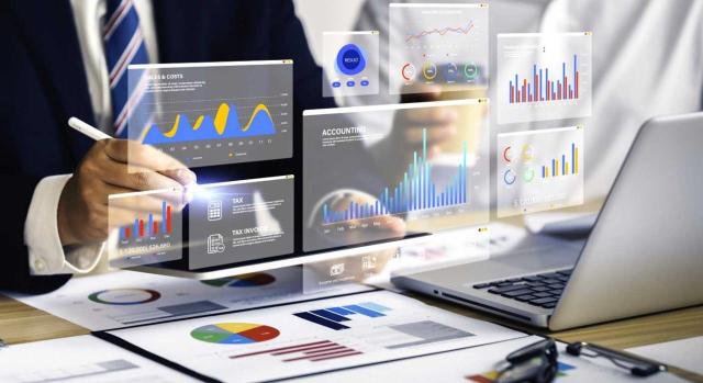 La Administración Tributaria puede pedir los documentos de una due diligence El TEAC analiza los requerimientos de información tributaria en operaciones societarias. Imagen de dos hombres en un escritorio con su portatil rodeados de gráficos