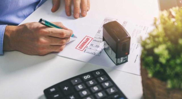 El acta notarial de remisión por correo es suficiente para entender demostrada la voluntad de cobro y reclamación al deudor de un crédito incobrable. Imagen de  un hombre aprobando una factura con un sello