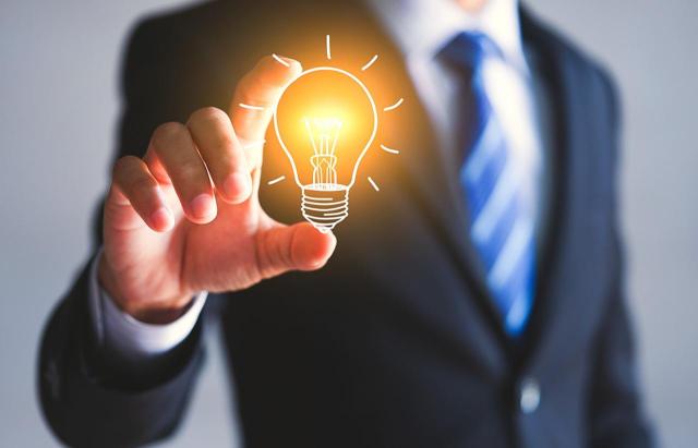 No sujeto a IVA: administrador único y director general bajo RETA Las retribuciones de un administrador únicos, que desempeña funciones de dirección general y que está bajo el RETA, no están sujetas al IVA. Imagen de una bombilla encendida en la mano de un hombre