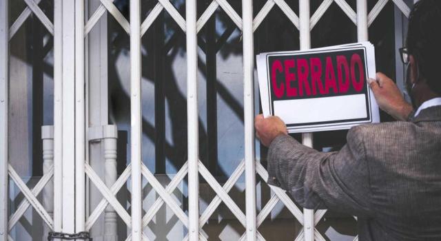 Entidad que lleva años sin actividad: se requiere la presentación del modelo 036 para dejar de presentar el modelo 303. Imagen de un hombre poniendo el cartel de Cerrado en un establecimiento