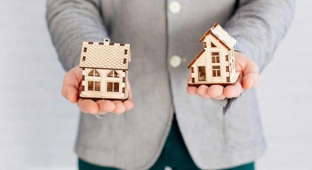 Exención por reinversión en vivienda habitual para no residentes: no es válido justificar el incumplimiento del plazo de los dos años alegando motivos laborales, excepción que sólo aplica al plazo de los tres años. Imagen de un hombre con unas casas en sus manos