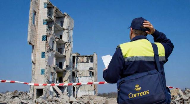 El TSJ de Madrid considera no conforme a derecho una notificación por eludir la AEAT el carácter residual de la notificación por edicto. Imagen de un hombre de correos mirando con cara de preocupación un edificio derruido en el que ve que no puede entragar su entrega