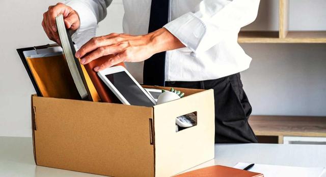 Imputación temporal de las provisiones por despido improcedente en el ámbito del IS: ¿deben deducirse en el ejercicio del despido o en el del acuerdo de conciliación? Imagen de un hombre metiendo sus pertenencias en una caja tras su despido