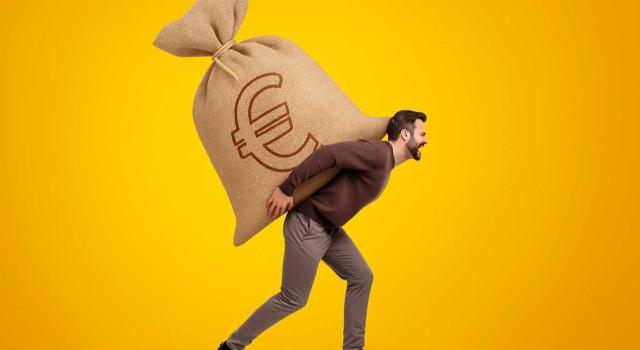 La exención del art. 7 d) de la Ley IRPF no se aplica a indemnizaciones percibidas por el trabajador si se cuantifican en función de los salarios dejados de percibir por el retraso empresarial de reincorporación tras una excedencia. Imagen de un hombre llevando una saca de dinero a sus espaldas