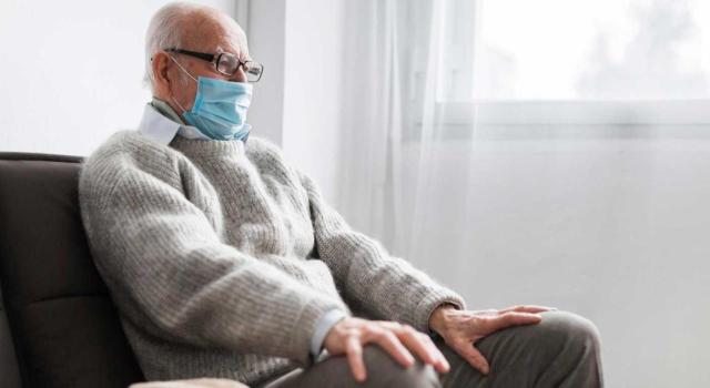 Si se acreditan circunstancias excepcionales que motivan el cambio de residencia se mantiene la exención para los mayores de 65 años Si se acredita que el cambio de residencia hace más de dos años obedeció a circunstancias ajenas a la voluntad del mayor de 65 años la vivienda habitual mantendría dicha consideración y su transmisión estaría exenta. Imagen de un señor mayor sentado en un sillon con mascarilla puesta