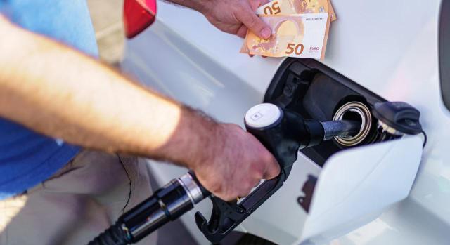 La Audiencia Nacional ha resuelto que no procede la devolución del tramo autonómico de hidrocarburos a las operadoras al quedar acreditado que lo repercutieron a sus clientes. Imagen de un hombre hechando gasolina al coche y en la otra mano, 100 euros