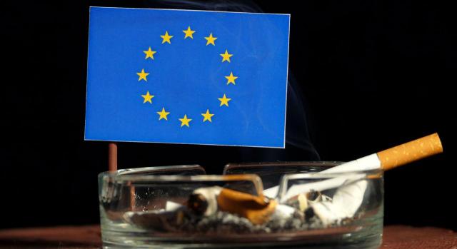 Impuesto especial que grava el tabaco. Cenicero con un cigarrillo y al fondo una bandera de la UE