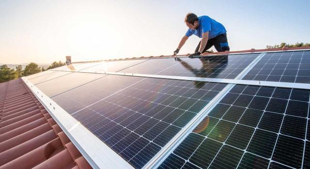 IRPF, deducciones. Imagen de un trabajador profesional instalando paneles solares en el techo de una casa