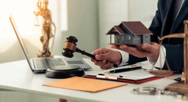 TEAC: ¿qué pasa con una diligencia de embargo cuando una de las deudas ha sido anulada? Una diligencia de embargo se mantiene de forma parcial cuando alguna de las deudas incluidas en ella haya sido anulada según la doctrina consolidad del TEAC. Imagen de un juez en el que en una mano tiene el mazo y en la otra una casa