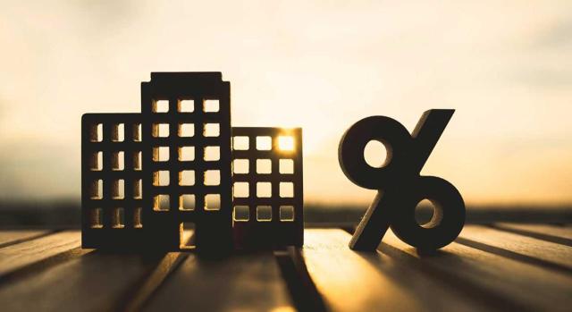 Tipo de gravamen de IVA aplicable en caso de contrato de arrendamiento financiero con opción de compra suscrito por una sociedad que destina el edificio integrado por viviendas y locales al subarrendamiento. Imagen de unos ladrillos y el símbolo del porcentaje sobre el atardecer de fondo