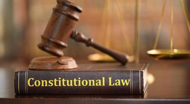 IIVTNU: las autoliquidaciones no impugnadas antes de la STC 182/2021, de 26 de octubre de 2021, no pueden revisarse con base exclusiva en la declaración de inconstitucionalidad. Imagen del libro de la Constitución al lado del mazo y la balanza del juez