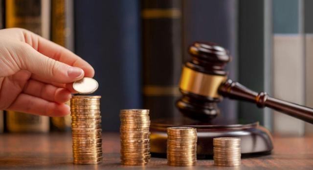 El dies ad quem del devengo de intereses de demora en el caso de liquidaciones tras un acta en disconformidad es la fecha del acuerdo de liquidación EL TS establece como jurisprudencia que ell día final o dies ad quem del devengo de intereses de demora correspondiente a las liquidaciones que se derivan de un acta suscrita en disconformidad es la fecha del acuerdo de liquidación. Imagen de unos montocitos de monedas con un mazo al lado