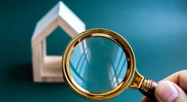 Incremento del justiprecio por retasación de los bienes expropiados tras fallecimiento del titular: IRPF o ISD. Imagen de una lupa mirando hacia una casa